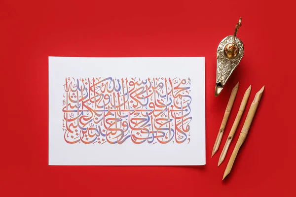 Paper with Arabic text and tools for calligraphy on color background