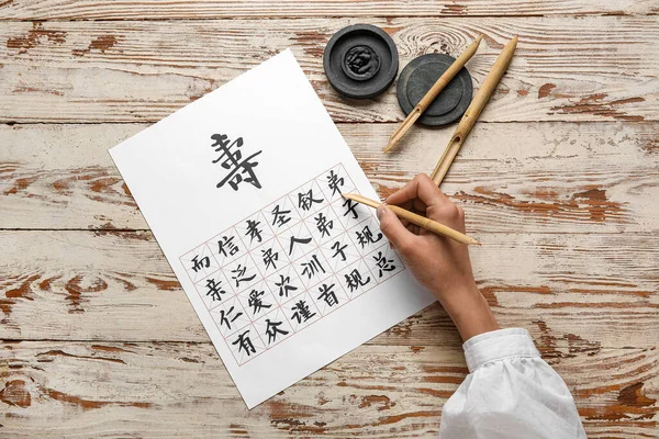Asiatischer Kalligraph Schreibt Hieroglyphen Auf Holzgrund — Stockfoto