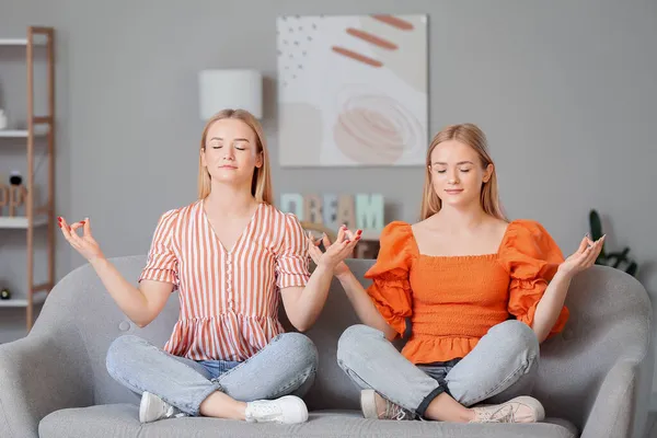 Jovens Irmãs Gêmeas Meditando Sofá Casa — Fotografia de Stock
