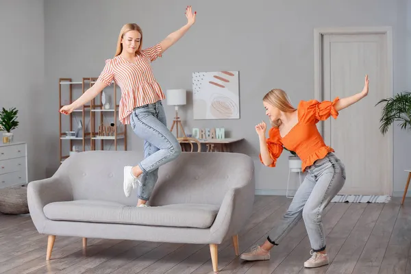 Young twin sisters dancing at home