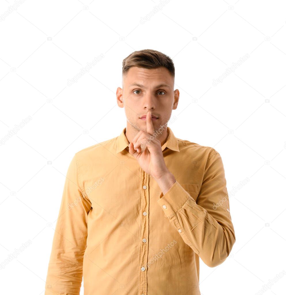 Young man showing silence gesture on white background