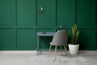 Rahat işyeri ve yeşil duvarın yanındaki ev bitkisi olan bir oda.