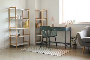 Modern iş yeri, raf üniteleri ve koltuk olan bir oda.