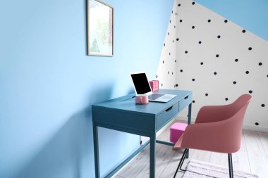 Fincan, dizüstü bilgisayar, takvim masanın üstünde ve sandalye renk duvarının yanında.