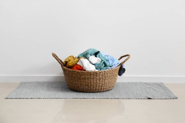 Açık duvarın yanındaki mavi halıda kirli sepet.