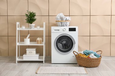 Çamaşır makinesi ve hasır sepeti olan modern banyonun içi.