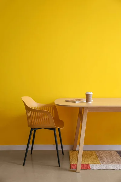 Matbord Med Papperskopp Kaffe Och Magasin Nära Gul Vägg — Stockfoto