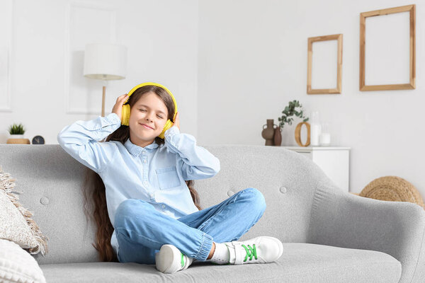 Funny little girl listening to music at home