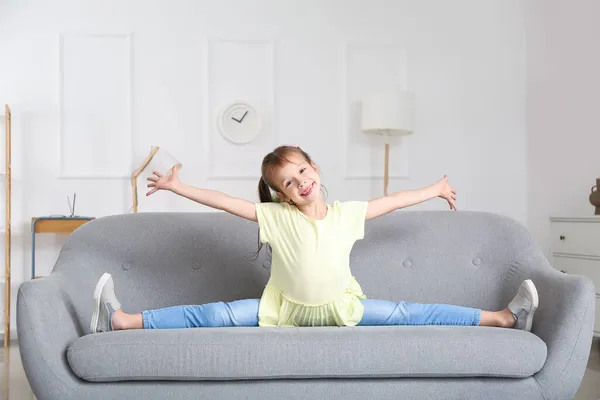 小女孩在家里的沙发上做腿劈开的事 — 图库照片