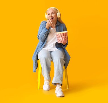 Olgun bir kadın arka planda lezzetli patlamış mısır yiyor.