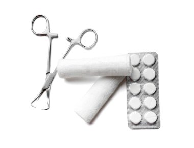 Cerrahi alet, tıbbi gazlı bez ruloları ve beyaz arka planda haplar.