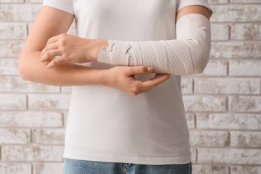 Duvarın arkasında eli bandajlı genç bir kadın.