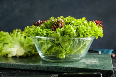 Koyu arkaplanda taze marul olan cam kase.