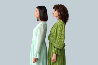 Gri arka planda duran güzel kız kardeşler