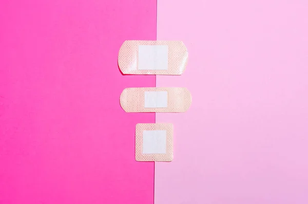 Adhesive medical plasters on pink background