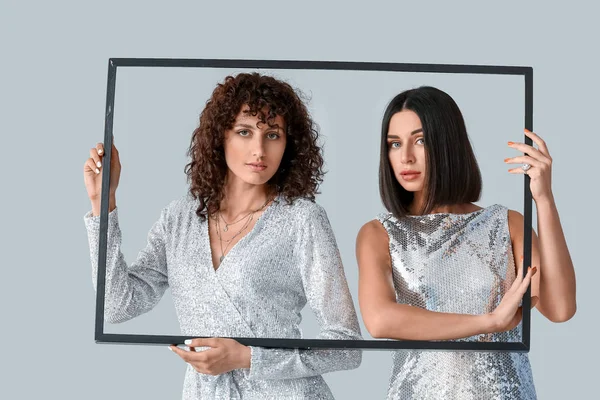 Hermosas Hermanas Sosteniendo Marco Sobre Fondo Gris — Foto de Stock