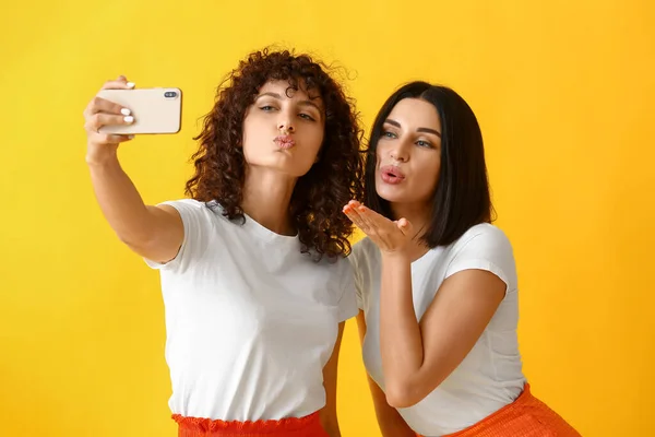 Young Sisters Giving Air Kiss Taking Selfie Color Background — Stock Photo, Image