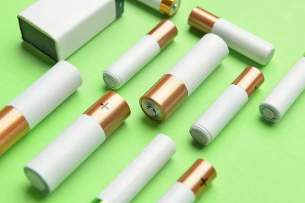 Different Alkaline Batteries Green Background — Stock Photo, Image
