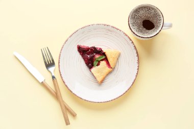 Lezzetli bir parça erik galeti ve renkli arka planda bir fincan kahve.