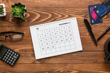 Kasım 2021 takvim sayfası, kredi kartları ve siyah ahşap arka planda kırtasiye malzemeleri. Kara Cuma