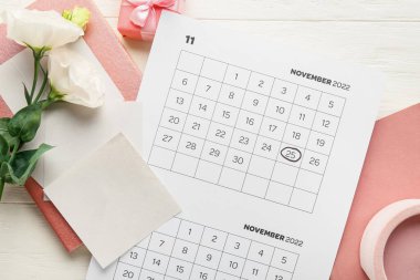 Kara Cuma işaretli takvim sayfası ve beyaz ahşap arka planda çiçekler