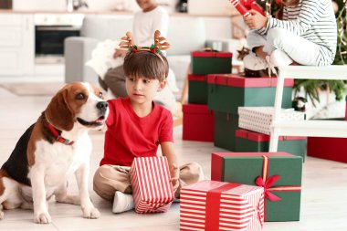 Noel arifesinde evde hediyeleri ve köpeği olan sevimli küçük bir çocuk.