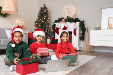 Noel arifesinde evde hediyeleri olan sevimli küçük çocuklar.