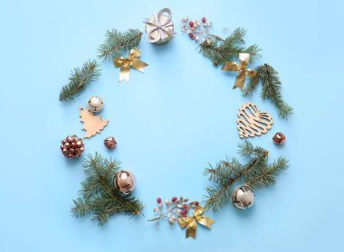 Mavi arka planda Noel süslemeleri ve kozalaklı dallardan yapılmış çerçeve