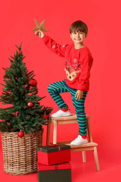 小男孩用红色的背景装饰圣诞树 — 图库照片
