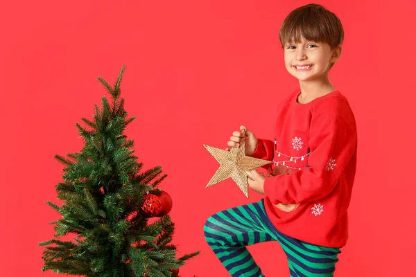 小男孩用红色的背景装饰圣诞树 — 图库照片