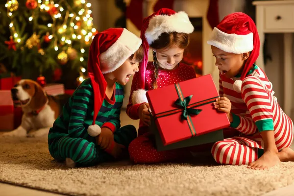 Überraschte Kleine Kinder Mit Nikolausmützen Öffnen Weihnachtsgeschenk Hause — Stockfoto