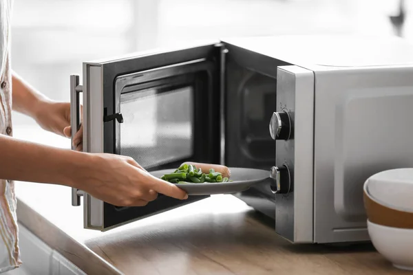 Wanita Muda Menempatkan Piring Dengan Makanan Dalam Oven Microwave Dapur — Stok Foto