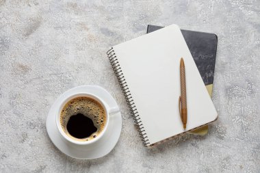 Bir fincan kahve, defterler ve arka planda bir kalem.