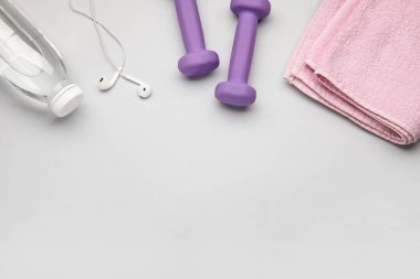 Dambıllar, kulaklıklar ve arka planda bir şişe su.