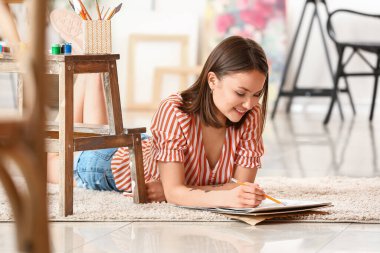 Atölyede çizim yapan genç bir kadın sanatçı