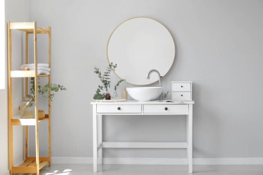 Yeşil okaliptüs dallı vazolar ve banyodaki masada lavabo.