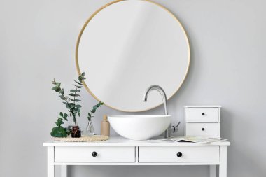 Yeşil okaliptüs dallı vazolar ve banyodaki masada lavabo.