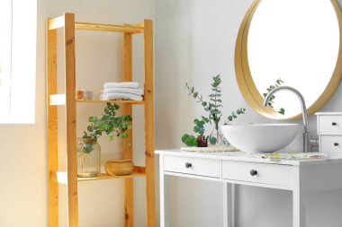 Yeşil okaliptüs dallı vazolar ve banyodaki masada lavabo.