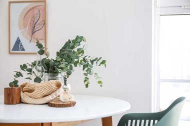 Mutfaktaki yemek masasında okaliptüs dalları olan vazolar.