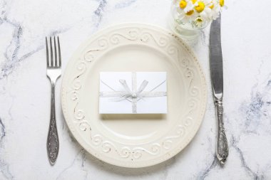 Düğün davetiyeli güzel bir masa ve arka planda papatya çiçekleri.