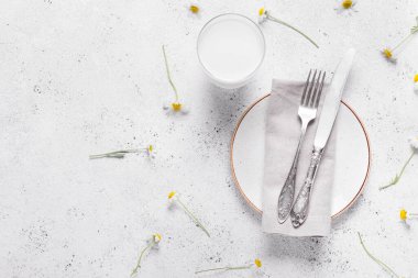 Çatal bıçak takımı ve beyaz arka planda papatya çiçekleri olan güzel bir masa.