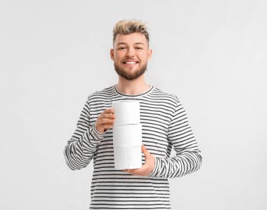 Arka planda tuvalet kağıdı olan genç bir adam.