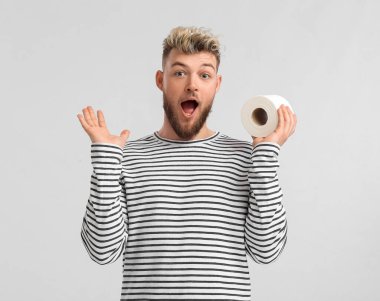 Arka planda tuvalet kağıdı olan genç adam şaşırdı.