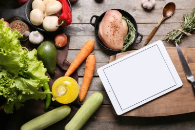 Tablet bilgisayar, taze sebzeler ve çiğ tavuk eti.