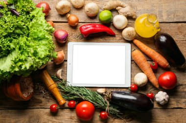 Tablet bilgisayarda ahşap masada lezzetli malzemeler var.