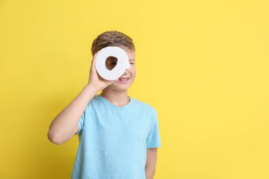 Sarı arka planda tuvalet kağıdı olan şirin bir çocuk.