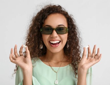 Hafif arka planda sakız çiğneyen havalı Afro-Amerikalı kadın.