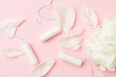 Adet tamponları ve pembe arka planda çiçek.
