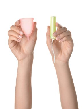 Adet bardağı ve beyaz arka planda tampon olan kadın elleri.