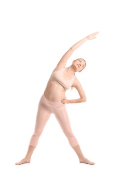 Güzel, hamile bir kadın beyaz arka planda yoga yapıyor.